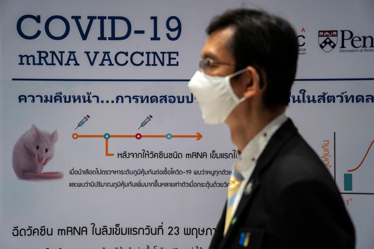 A man stands in profile with a white protective face mask on near a board showing progress in developing an mRNA vaccine candidate for COVID-19 during a news conference at the National Primate Research Center of Chulalongkorn University, in Saraburi province, Thailand, June 22, 2020. 