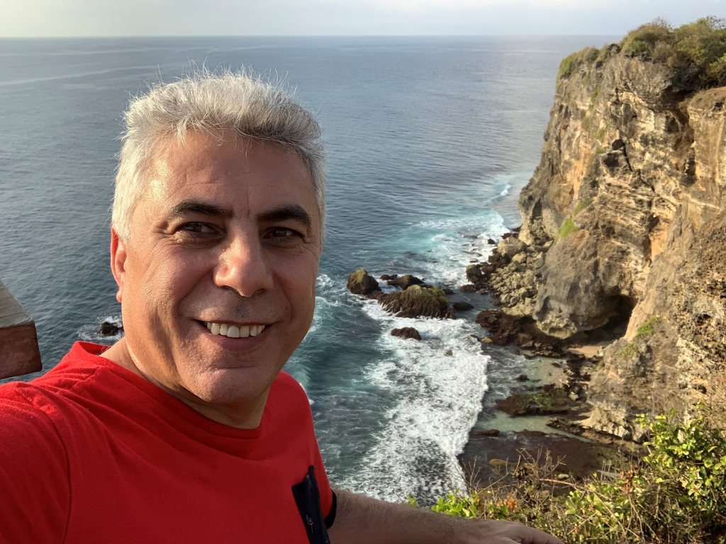 photo of the interview subject, Ali Mokdad, chief strategy officer for population health at the University of Washington in Seattle, and professor of health metrics sciences at IHME, outdoors overlooking the ocean and a cliff. 