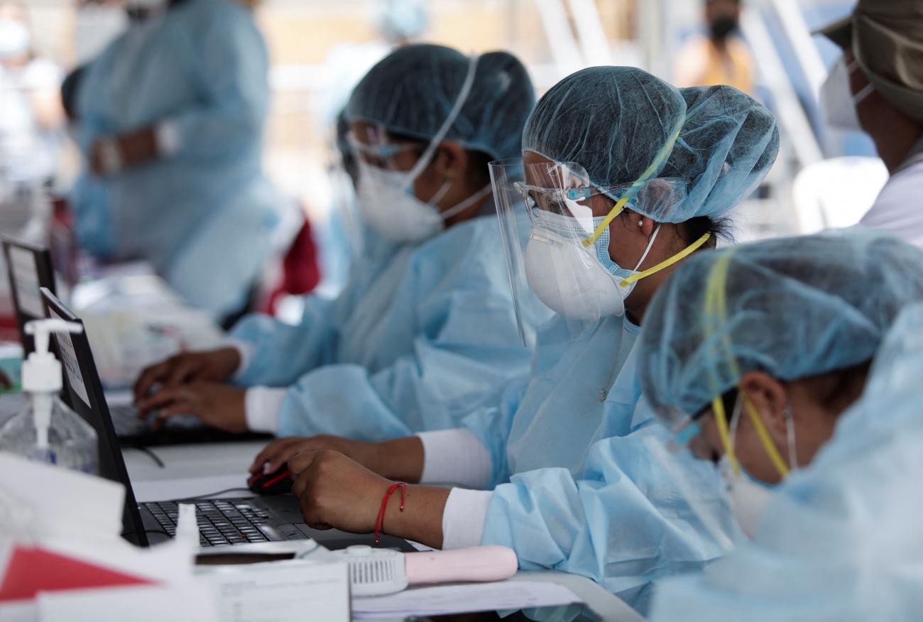 Health-care workers register people to be tested for COVID-19 as Peru raised its pandemic alert level in cities due to a third wave of infections due to omicron, in Lima, on January 6, 2022. 