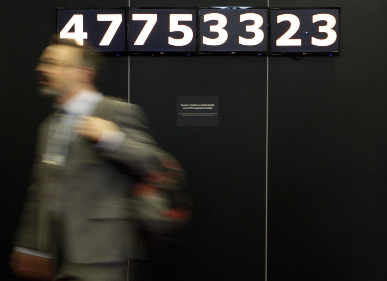 Delegates walk past the Death Clock before a Framework Convention Alliance meeting in Geneva March 15, 2010. The Death Clock counts the number of tobacco-related deaths since October 25, 1999. 