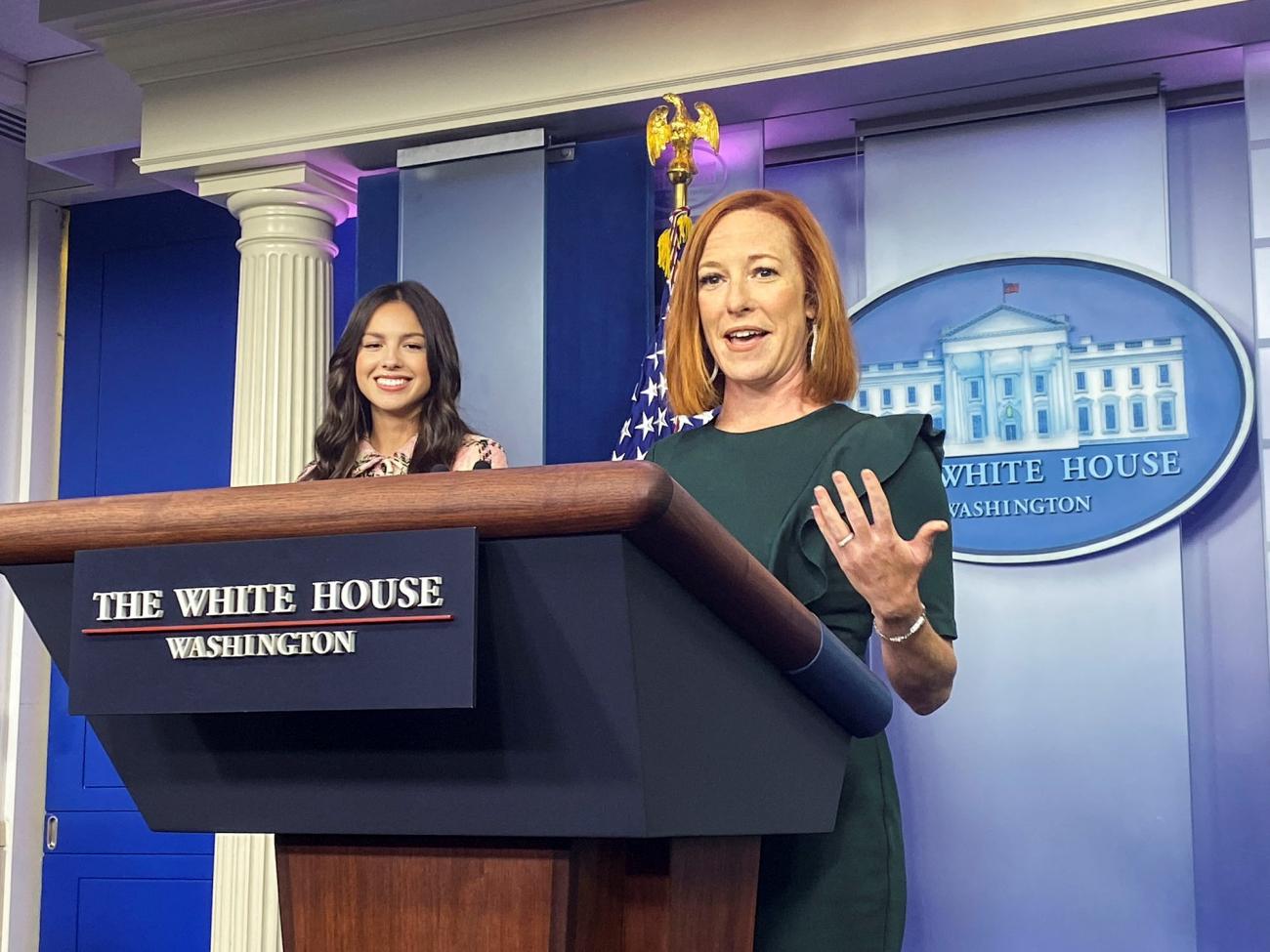 Singer Olivia Rodrigo and White House Press Secretary Jen Psaki stand at a podium at the White House
