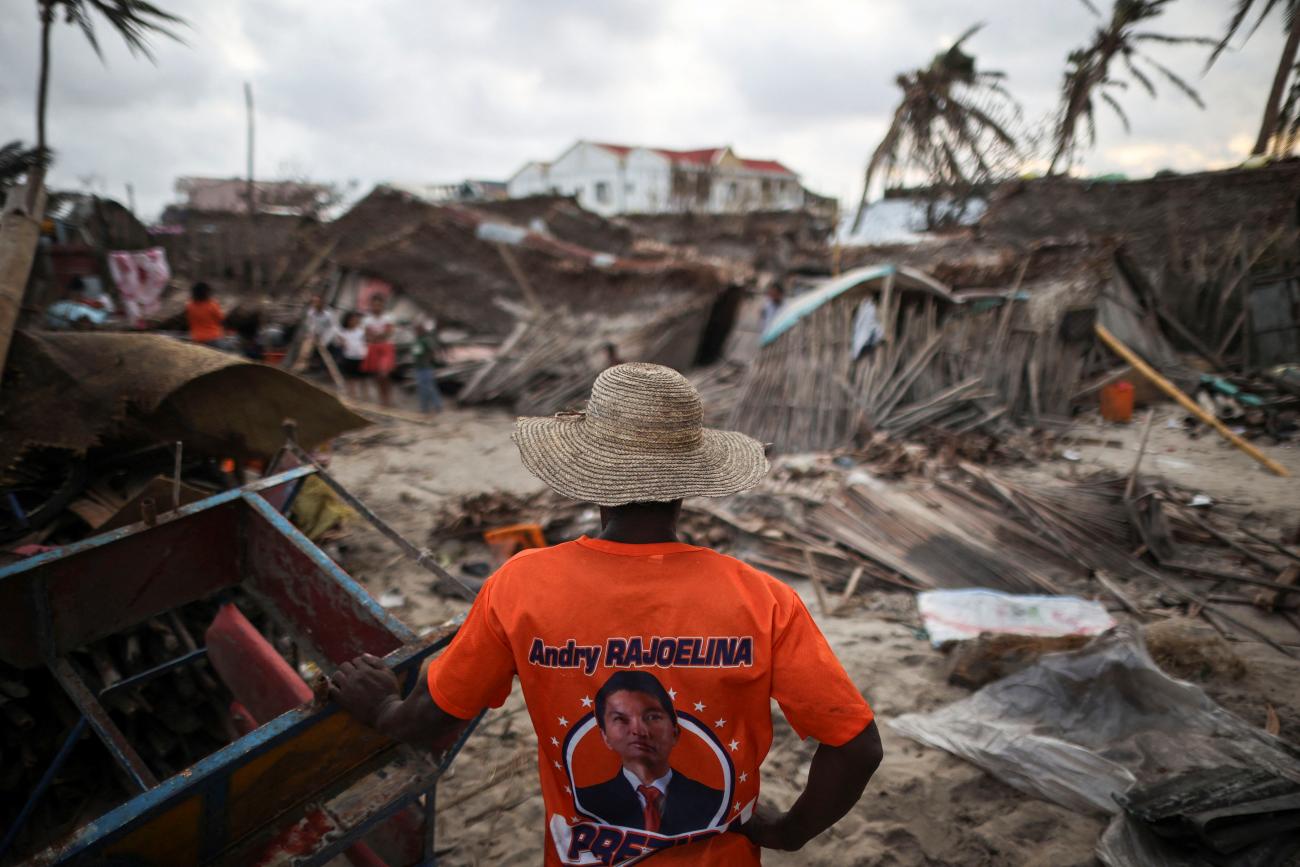 A man wearing a t-shirt with an image of Malagasy President Andry Rajoelina stands next to destroyed houses in the aftermath of Cyclone Batsirai, in the town of Mananjary, Madagascar, on February 7, 2022. 