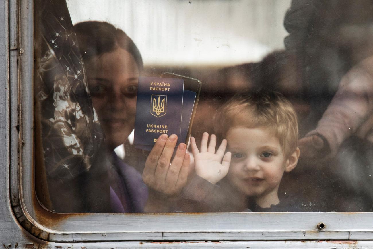 A woman with a toddler shows her Ukrainian passport as she looks on from a train window in in Przemysl, Poland.