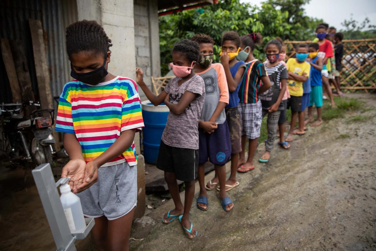 Students queue to sanitize their hands before a session at a learning center for Aeta community distance learning amid the COVID-19 pandemic, in Porac, Pampanga, Philippines, October 12, 2020.
