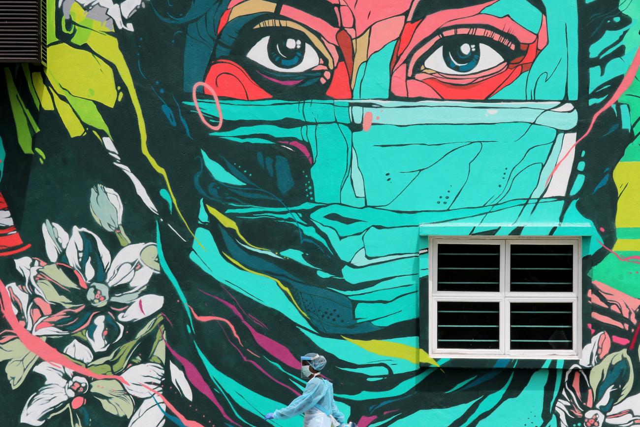 A medical worker passes by street art featuring a frontline worker in a mask outside a clinic in Kuala Lumpur, Malaysia, during the COVID-19 pandemic, on October 27, 2020.