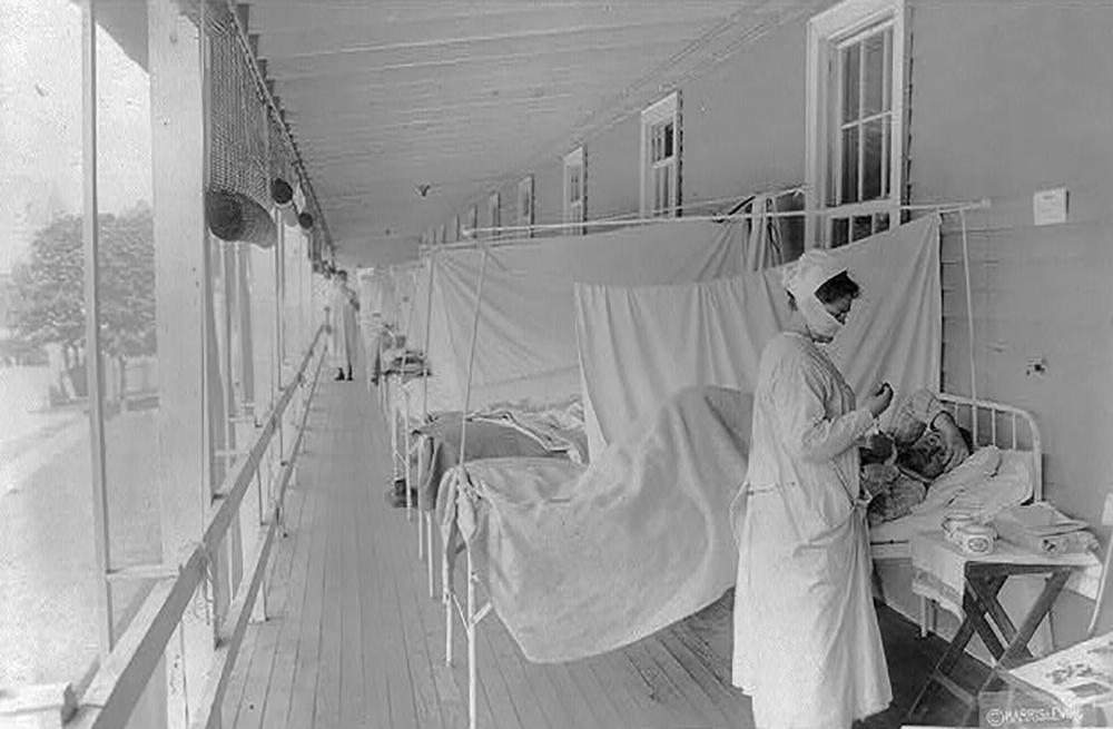 In a black and white photo from November 1918, a nurse takes the pulse of a patient in the influenza ward at Walter Reed Hospital during the influenza pandemic, in Washington, D.C.