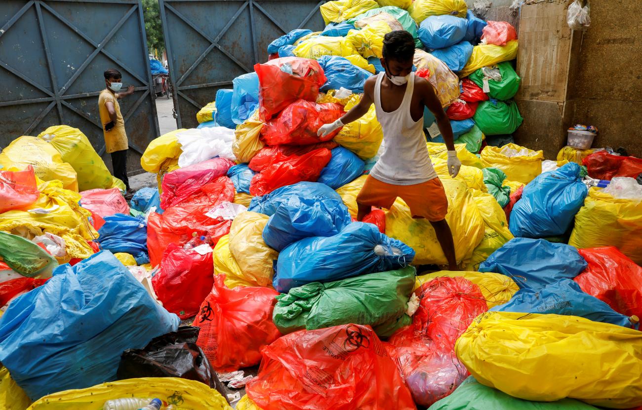 A waste collector walks over disposed medical waste bags inside a rubbish dump outside a hospital, during the COVID-19 outbreak, in New Delhi, India, July 17, 2020.