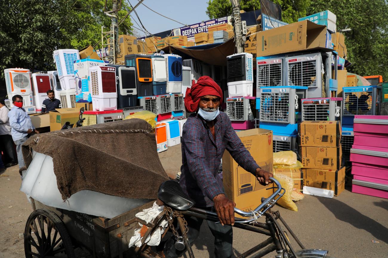 A man transports slabs of ice near an air cooler market on a hot summer day, in New Delhi, India, April 11, 2022