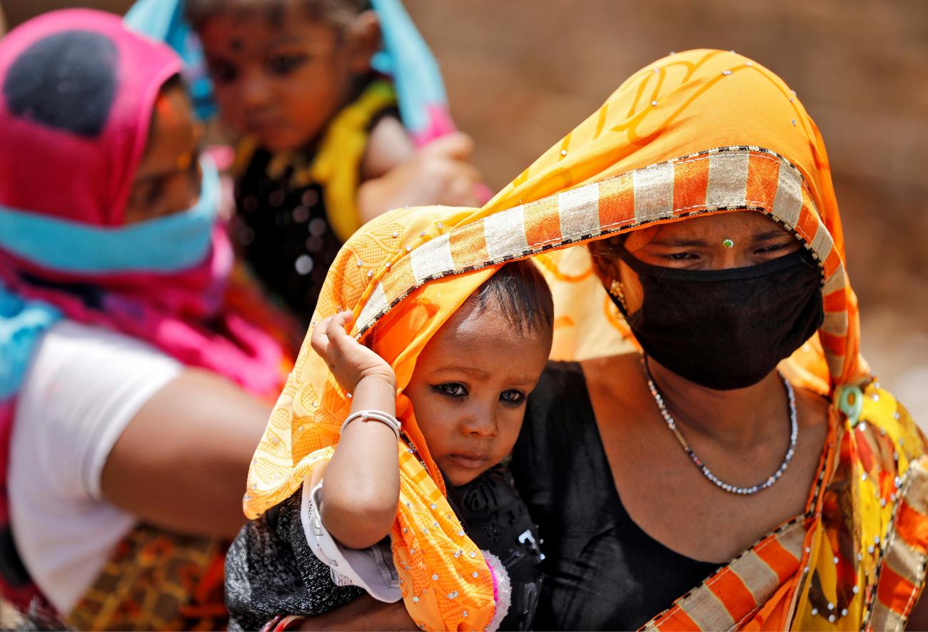 A mother drapes an orange sari over her baby to protect him from the heat  in Ahmedabad, India, May 20, 2020.