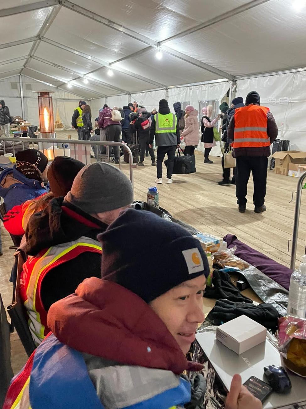 The author, Dr. Anthony Fong, bundled up in a warm hat and puffy jacket, sits at a table while on night shift with a team from Toronto-based, disaster-relief charity Canadian Medical Assistance Teams, at their pop-up clinic in Krakovets, near the Polish-Ukraine border in Lviv Oblast, Ukraine, March 2022.