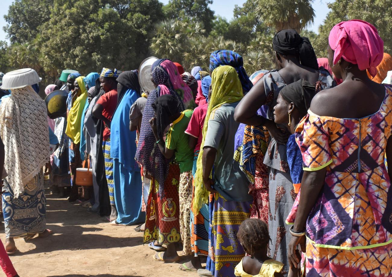 People from Cameroon, who fled deadly violence between Arab Choa herders and Mousgoum and Massa farming communities, queue to receive food at a refugee camp near Ndjamena, Chad, on December 13, 2021.