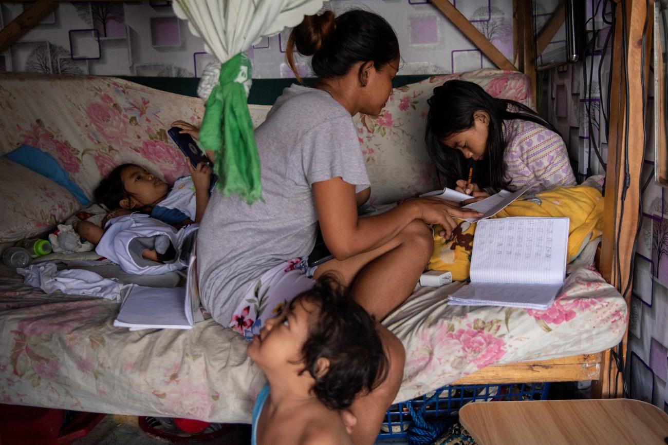 A mother helps her three children study on a floral couch during a school closure due to COVID-19 at their home in Manila, Philippines, November 10, 2020.