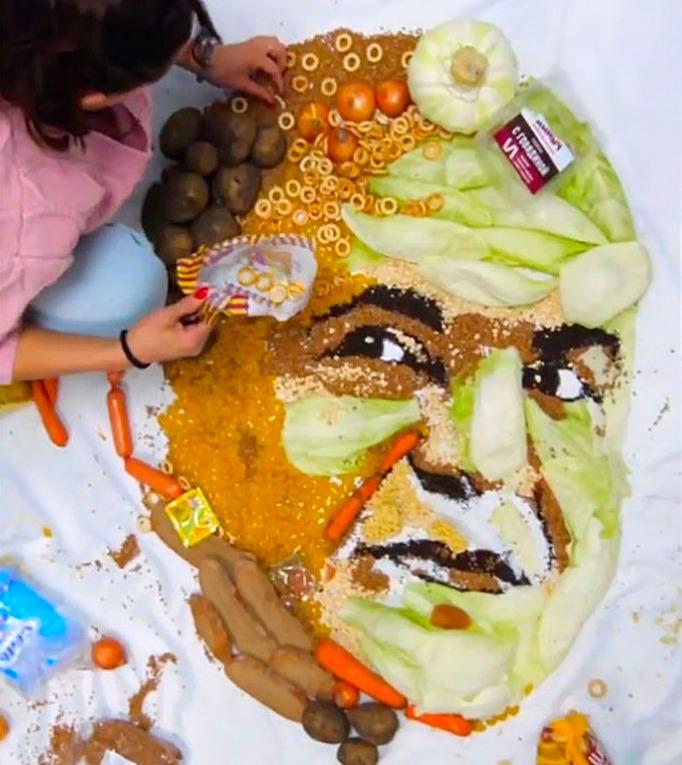 Artist Evgenia Skovart works on a portrait of Russian Prime Minister Mikhail Mishustin made of food to protest the rise in cost of living for Russians