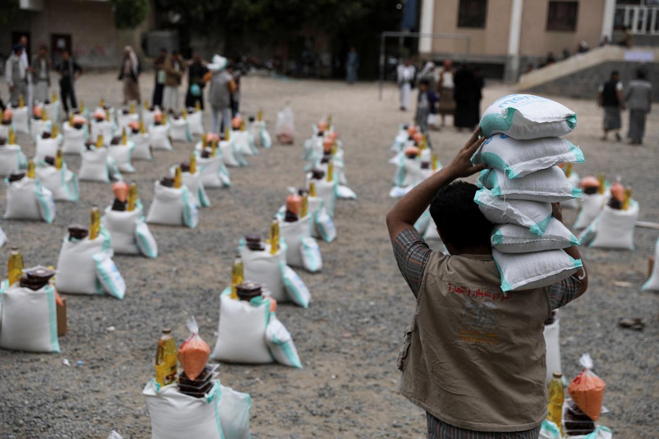 A worker carries sacks of sugar and rice during the distribution of food aid by the local charity, Mona Relief, in Sanaa, Yemen, on April 24, 2022