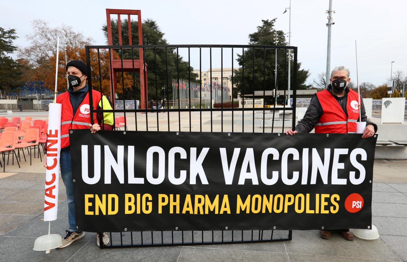 People hold a banner during a demonstration for an intellectual property rights waiver for COVID-19 vaccines and supplies aside from meeting of the Council for Trade-Related Aspects of Intellectual Property Rights (TRIPS) of the World Trade Organization (WTO) headquarters in Geneva, Switzerland, on November 30, 2021. 