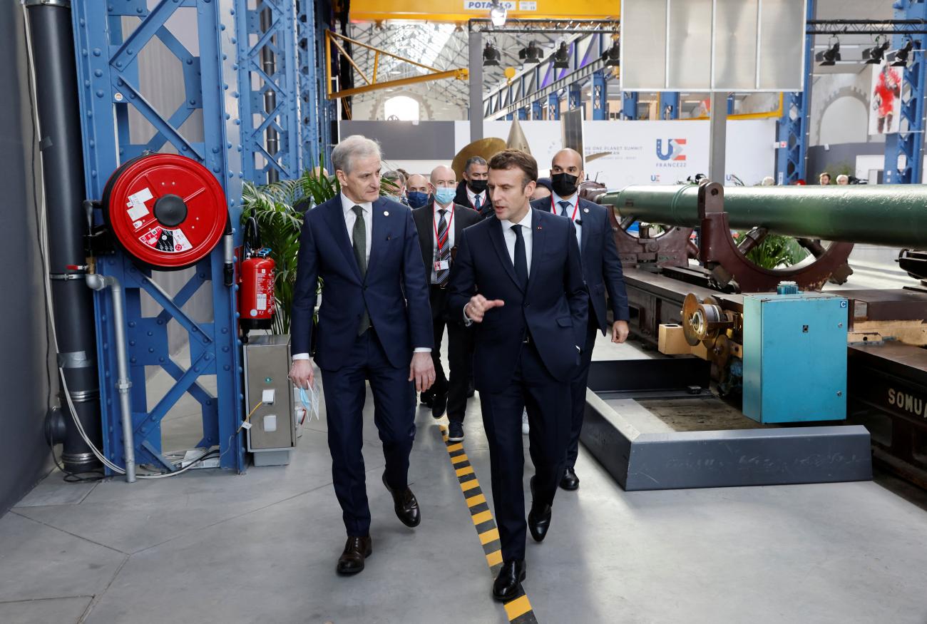 Norway's Prime Minister Jonas Gahr Store (L)  talks to France's President Emmanuel Macron (R) in an exposition space at  the One Ocean Summit.