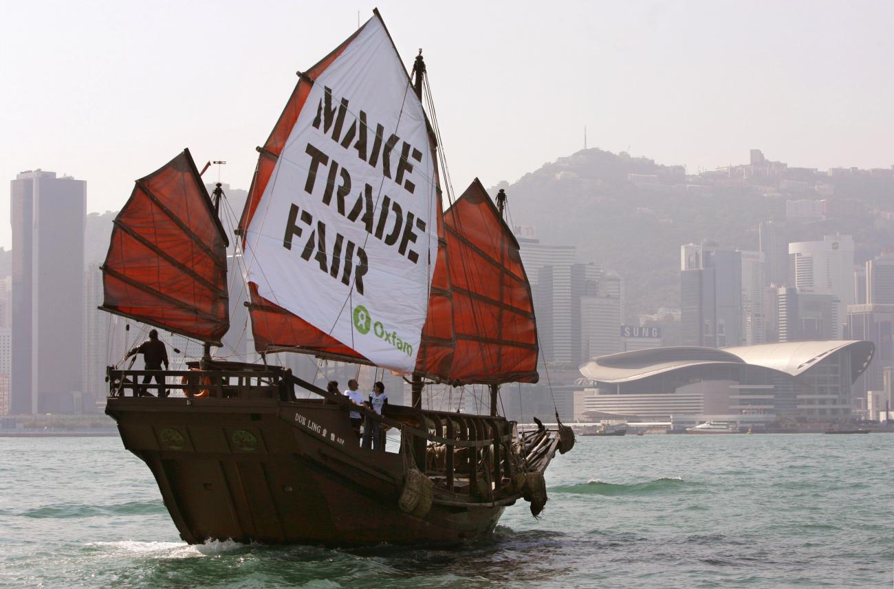A Chinese junk carrying a banner hoisted by international relief group Oxfam sails past the Hong Kong Convention and Exhibition Centre