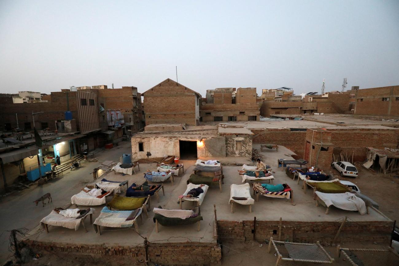 About twenty men sleep on charpoy rope beds, early in the morning during a heatwave, on the roof of a red brick building in Jacobabad, Pakistan, as temperatures reached 124 degrees Fahrenheit on May 15, 2022.