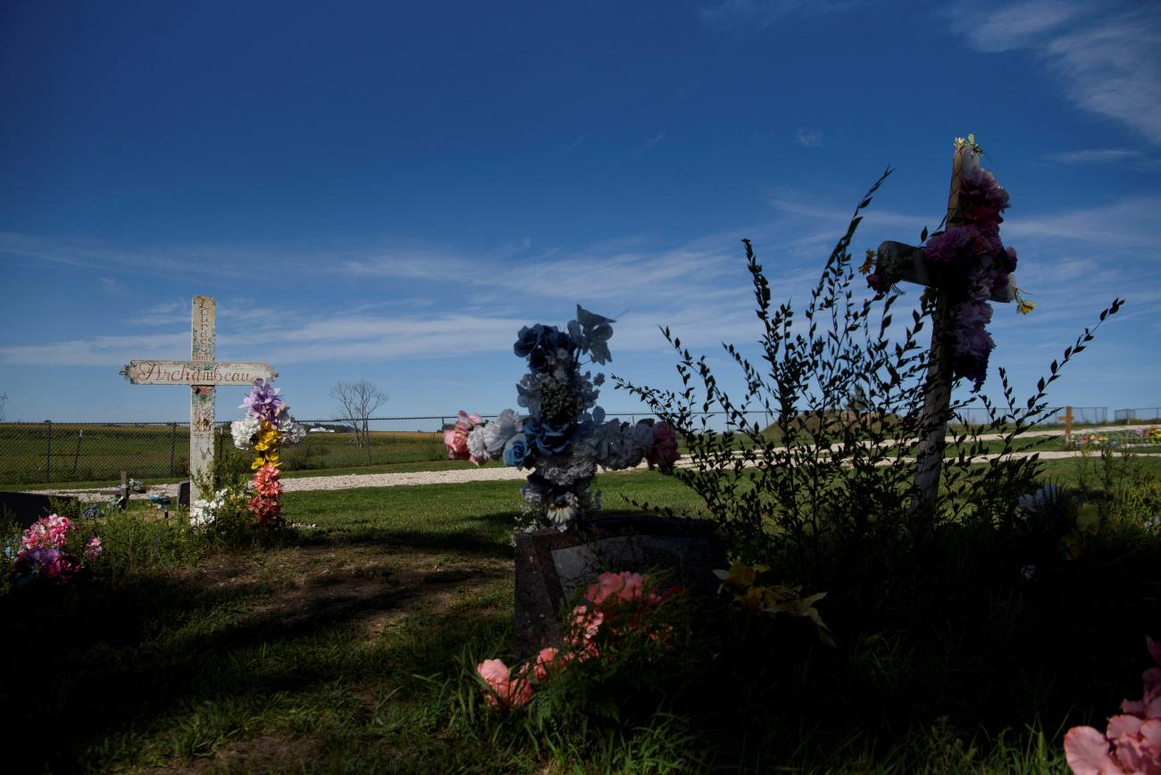 A deep blue sky stretches above a graveyard with large crosses adorned with flowers at St. Paul’s Catholic Church on the Yankton Indian Reservation in Marty, South Dakota, on September 8, 2021.