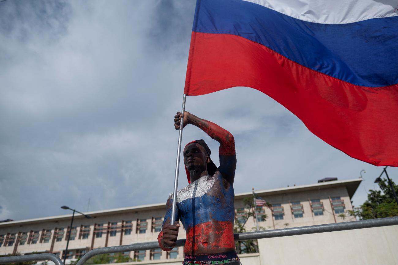 A man with the colors of the Russian flag painted on his body waves the Russian flag in front of the U.S. Embassy during a protest demanding the resignation of Haiti's Prime Minister Ariel Henry after weeks of shortages in Port-au-Prince, Haiti, October 17, 2022. 