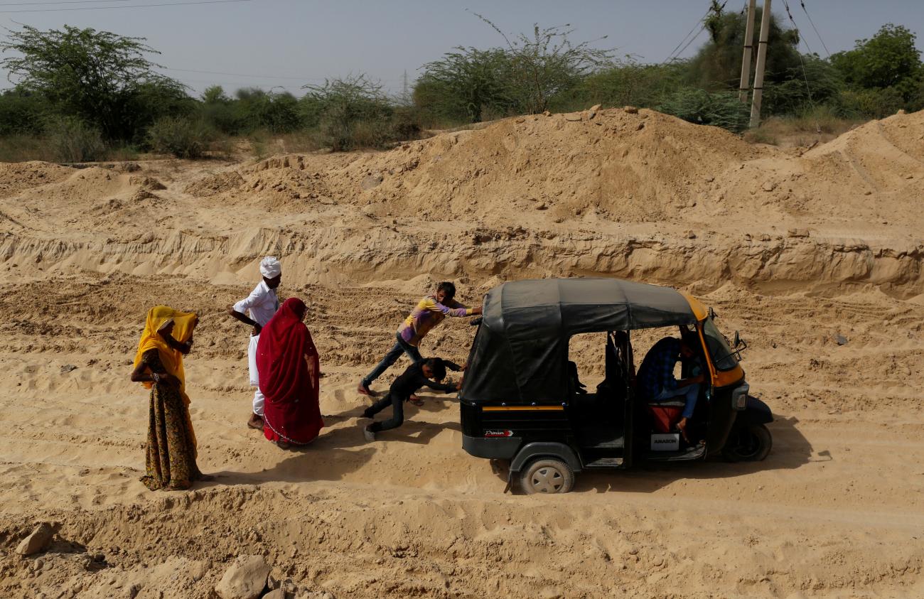 Bhawri Devi watches as her husband and son push an auto-rickshaw which got stuck in the sand on the way home from receiving cancer treatment, in a village in Jalore, India, on April 7, 2018. 