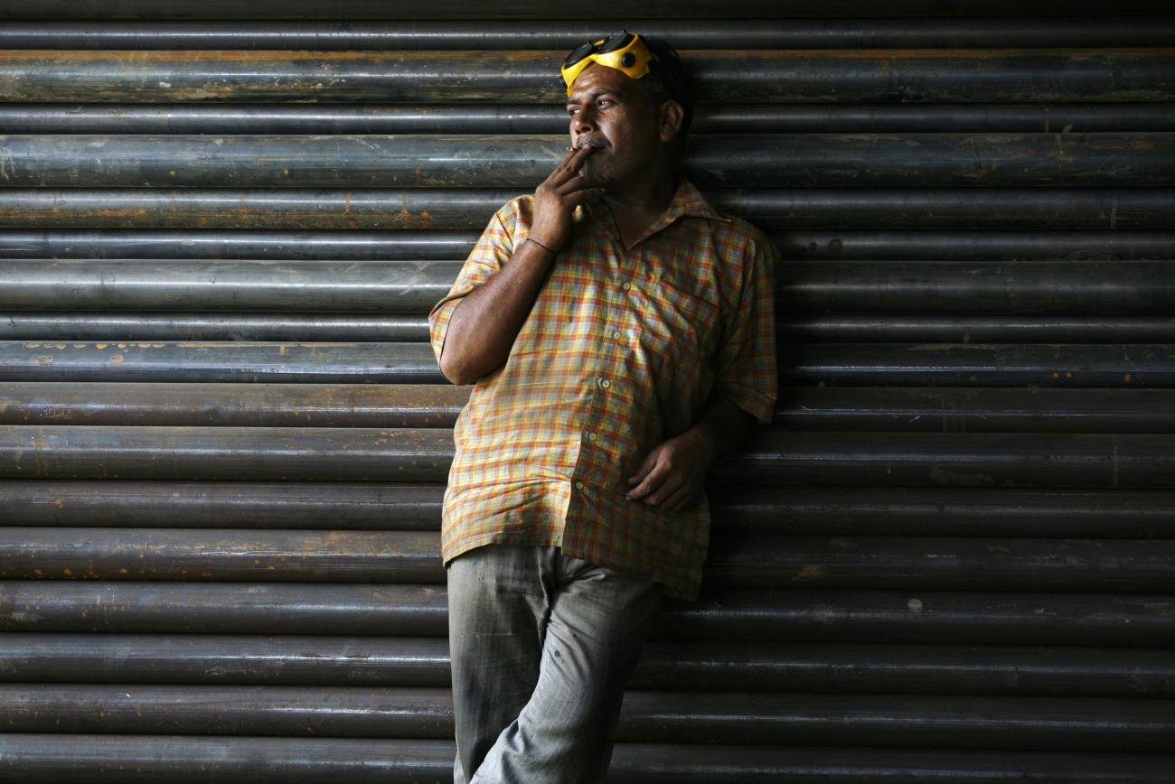 On a break at an iron workshop, a worker leans against a wall and smokes a bidi, a local hand-rolled cigarette with leaf tobacco, in Noida, on the outskirts of New Delhi, India.REUTERS/Parivartan Sharma