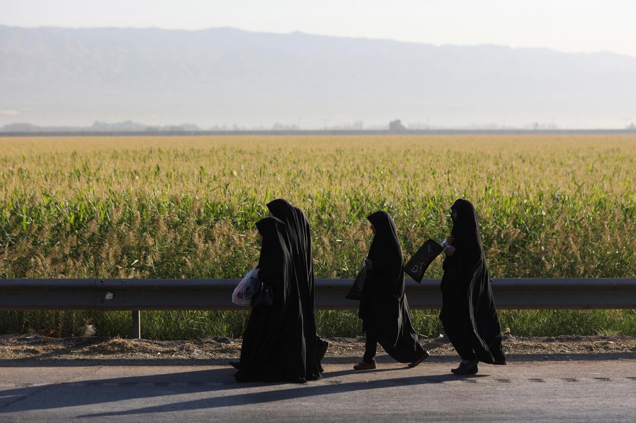 Women walk by a green field and hold flags to commemorate Arbaeen, a religious holiday, in southern Tehran, Iran September 17, 2022.