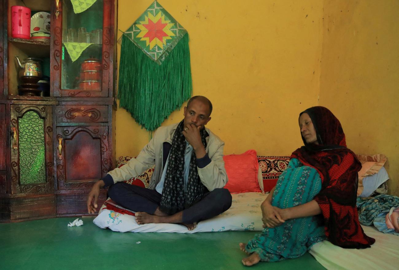 Jemal Abdella and his wife Tirungo Ambaye sit on a green floor in a room with yellow walls. They are mourning the loss of their daughter Zara, 17, who was killed by Tigray People's Liberation Front forces for resisting rape. Photo taken near Lalibela town, Ethiopia,  January 26, 2022. 