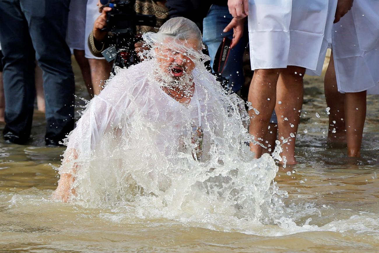 A pilgrim takes a dip in the waters of the Jordan River during a baptism ceremony at the Qasr el-Yahud site, near Jericho, in the Israeli-occupied West Bank as seen from the East Bank, Jordan January 18, 2019.