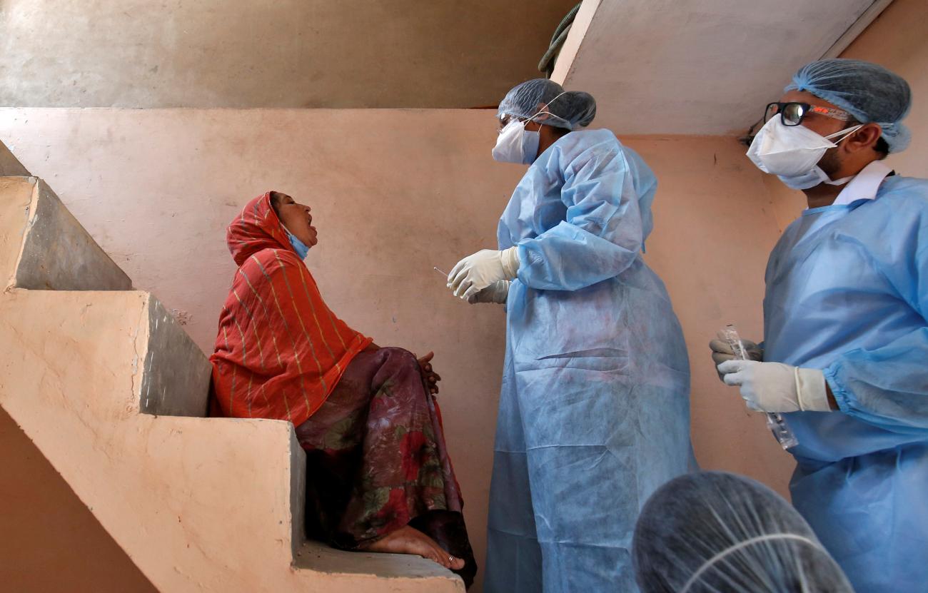 Doctors wearing protective gear prepare to take a swab from a woman to test for coronavirus disease (COVID-19) at a residential area in Ahmedabad, India, April 9, 2020. 