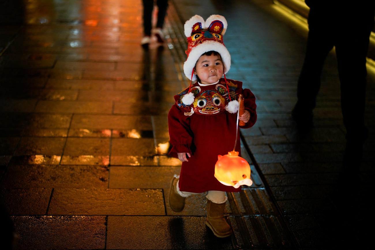 A child in a tiger costume walks with a lantern ahead of the Chinese Lunar New Year festivity at Yu Garden in Shanghai, China, January 28, 2022.