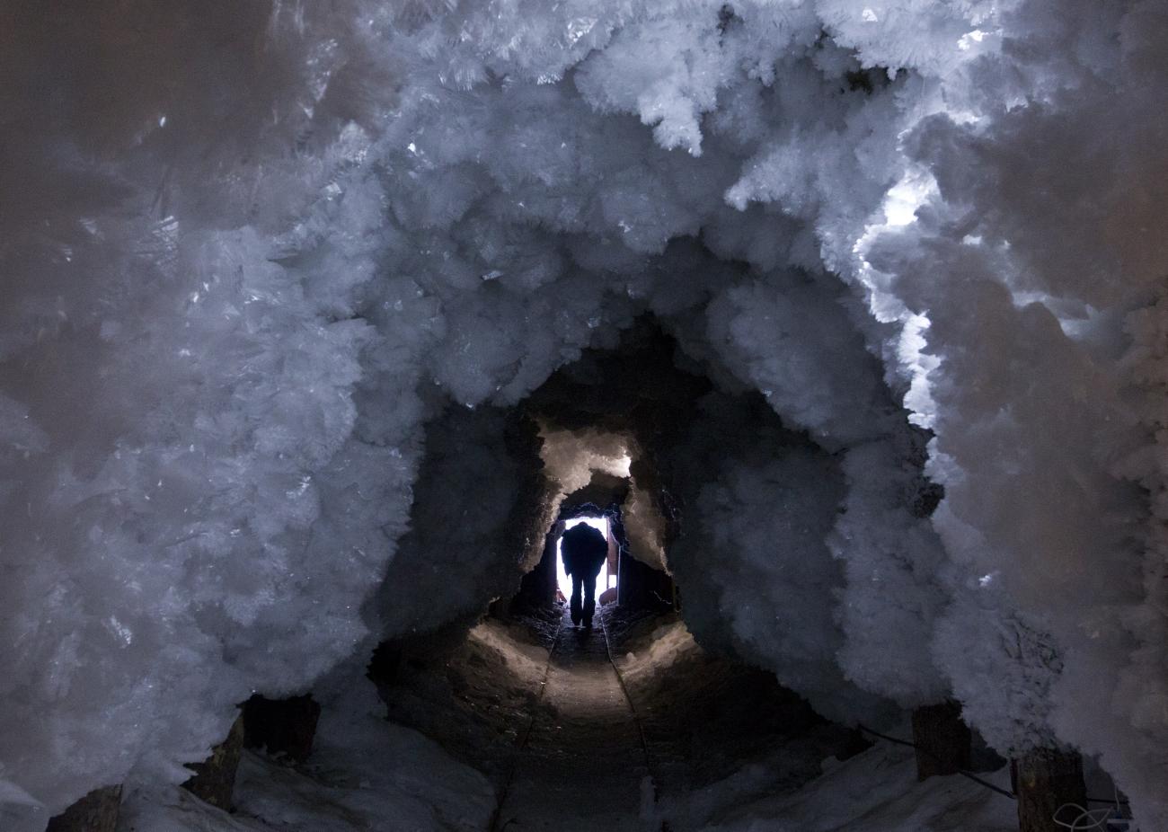 A man walks through a tunnel in permafrost covered with ice crystals