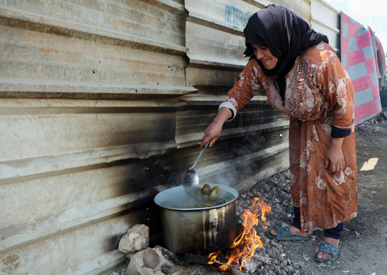 A woman boils eggplant at an informal camp for Syrian refugees in Qab Elias, Bekaa Valley, Lebanon, on October 18, 2022.