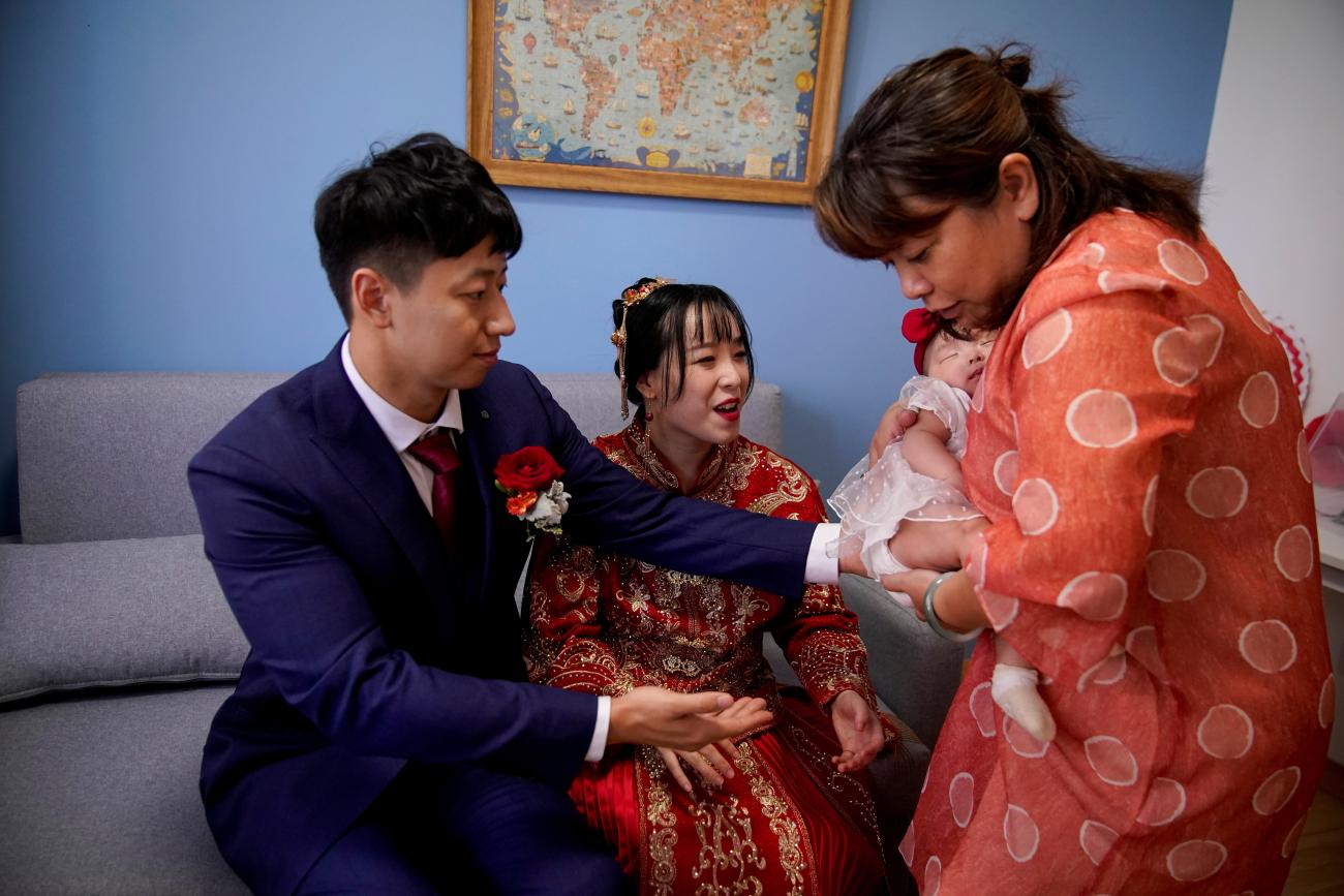 Pan Wenjun, thirty, and Wei Jiawen, twenty-nine, are handed their baby by Pan's auntie, on the day of their wedding, which had to be postponed due to the COVID-19 outbreak, in Shanghai, China, on August 16, 2020. REUTERS/Aly Song