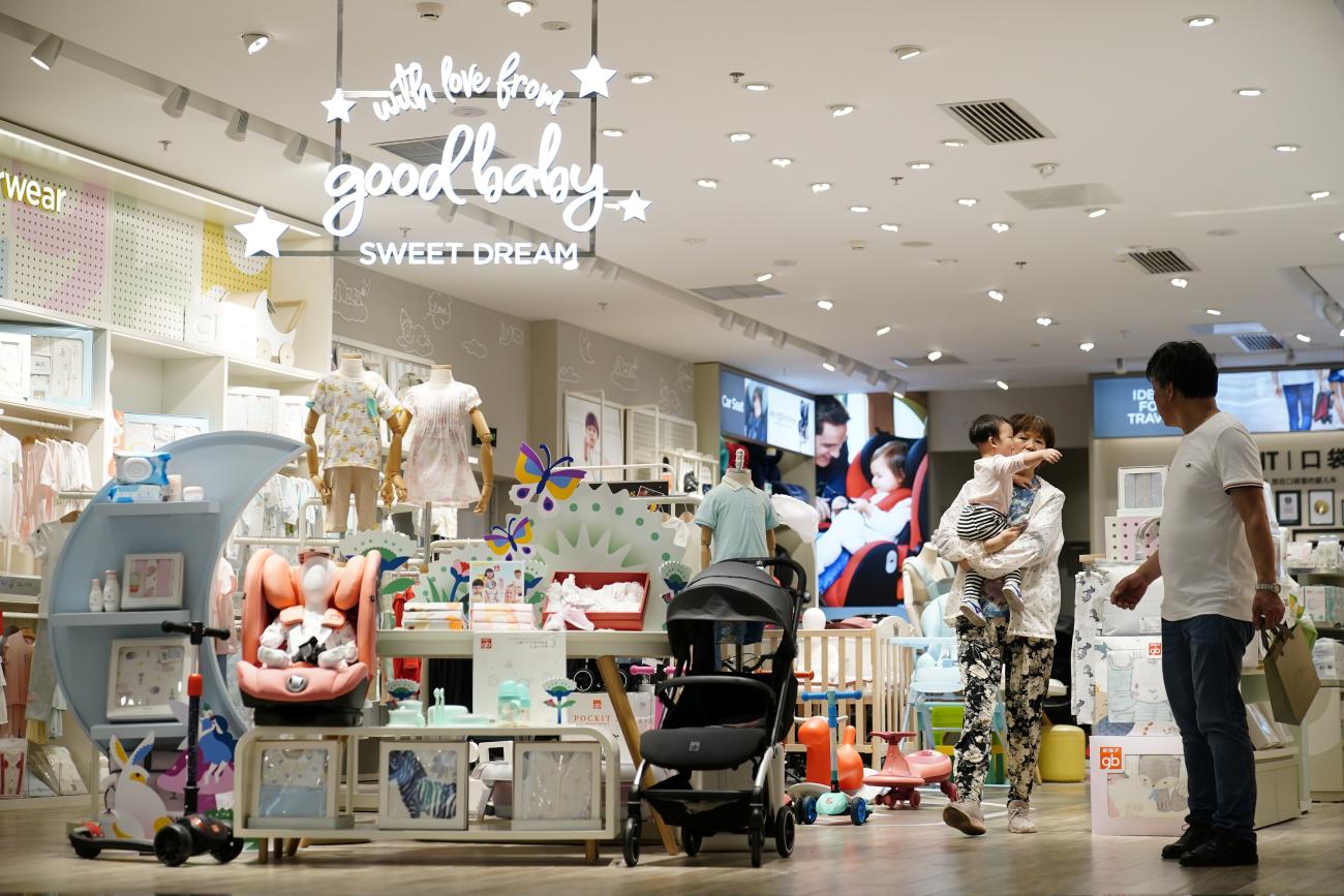 An adult holding a baby walks at a store selling baby products in Shanghai, China, on June 1, 2021. REUTERS/Aly Song