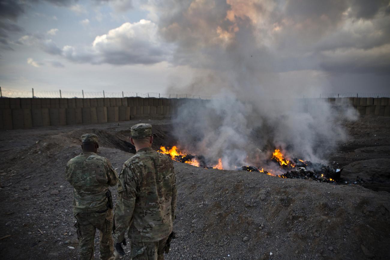 U.S. Army soldiers watch garbage burn in a burn pit at Forward Operating Base Azzizulah in Maiwand District, Kandahar Province, Afghanistan, on February 4, 2013. 