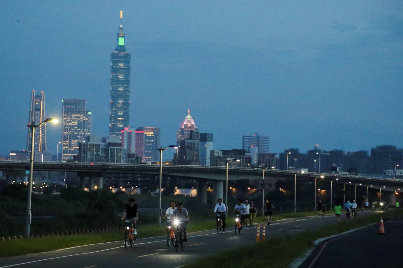 People bike on the river path during sunset hours in Taipei, Taiwan, on August 6, 2020. 