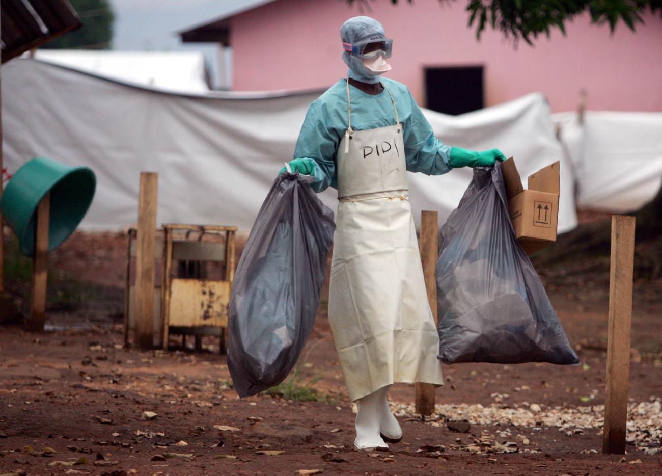 A health worker in protective clothing carries waste for disposal outside the isolation ward for patients with Marburg virus, in Uige, Angola, on April 20, 2005.