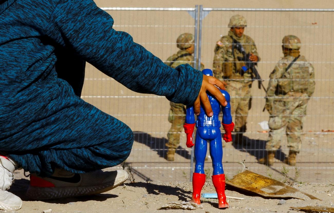 George, five, a migrant boy from Venezuela who is traveling with his family and trying to seek asylum in the United States, plays with a Captain America doll at the border between Mexico and the United States while members of the Texas National Guard stand guard on the banks of the Rio Bravo river, with the purpose of reinforcing border security and inhibiting the crossing of migrants to the United States, seen from Ciudad Juarez, Mexico, on December 27, 2022.
