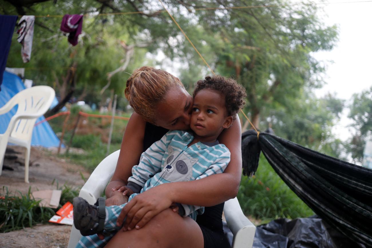 Venezuelan asylum seeker Alejandra Pena, thirty-four, kisses her son Natanael, one, next to their tent while they wait to attempt to cross into the United States by appointment through the Customs and Border Protection app, called CBP One, at a makeshift camp in Matamoros, Mexico, on June 20, 2023.