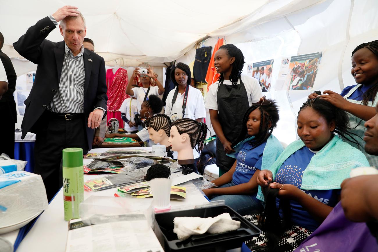 U.S. Ambassador to Kenya Robert Godec (L) talks with hair stylists as he visits a PEPFAR project for girls' empowerment, in Nairobi, Kenya, on March 10, 2018.