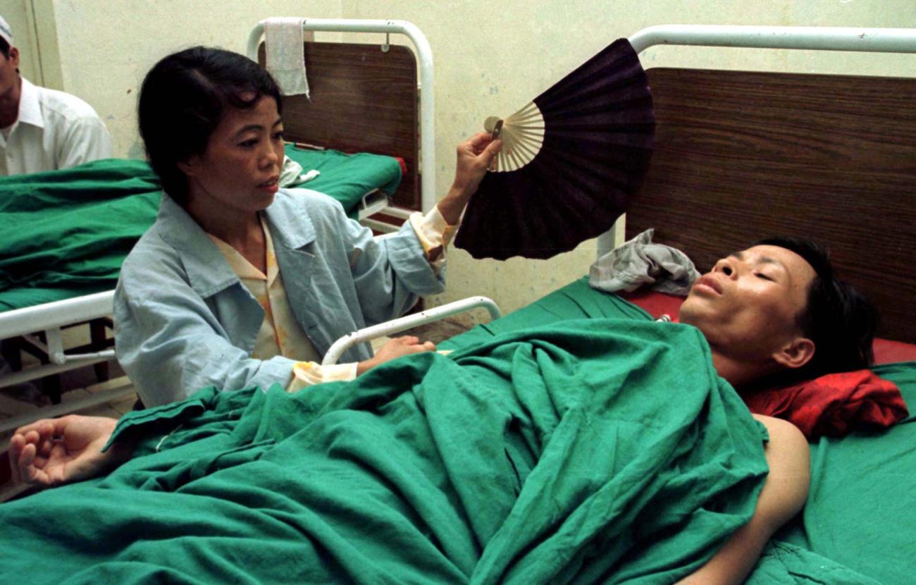 A Vietnamese man is fanned by his wife in the post-operative ward at Hanoi's Institute of Tuberculosis and Respiratory Diseases after a lung operation for complications caused by tuberculosis April 9.
