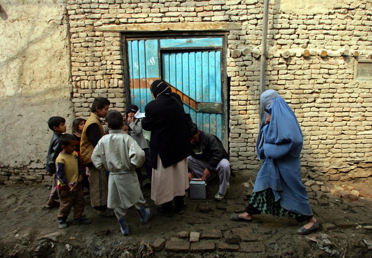 An Afghan health ministry worker (3rd-R, in black) goes door to door to administer polio vaccination drops to children during an anti-polio campaign in Kabul, Afghanistan March 5, 2006
