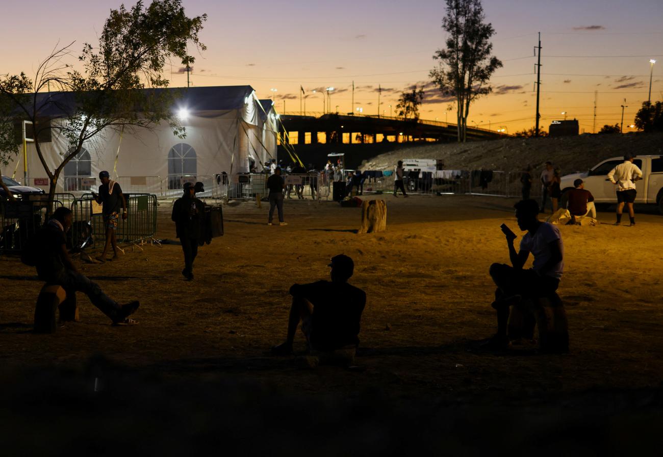 Migrants sit near a new shelter set up by local authorities to house migrants, mostly from Venezuela, who were evicted from a camp that was located in front of the migration detention center where migrants died during a fire in March, in Ciudad Juarez, Mexico, May 23, 2023.