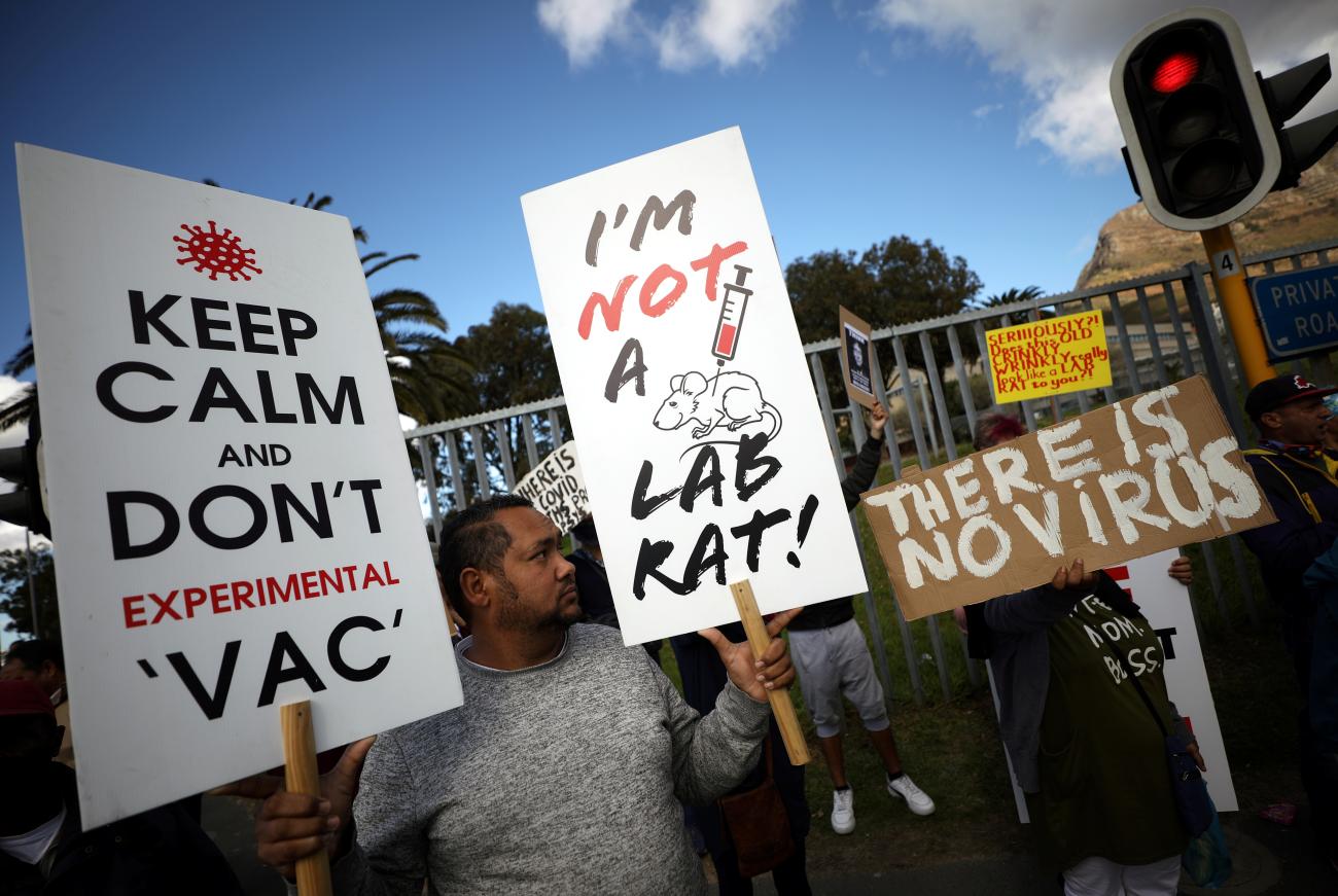 Protesters hold up homemade signs to protest the COVID-19 vaccine.