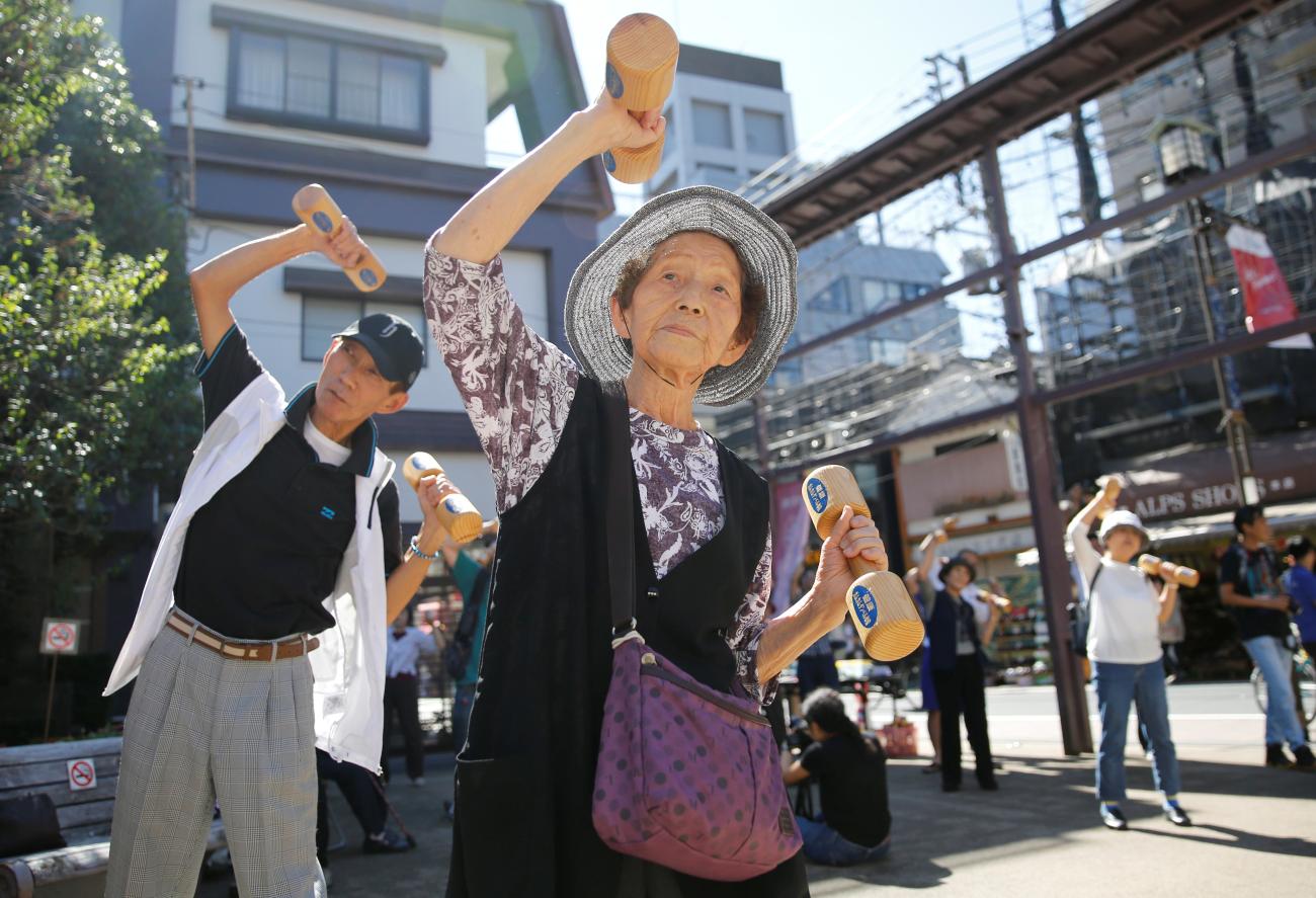 Elderly and middle-aged people exercise with wooden dumbbells.