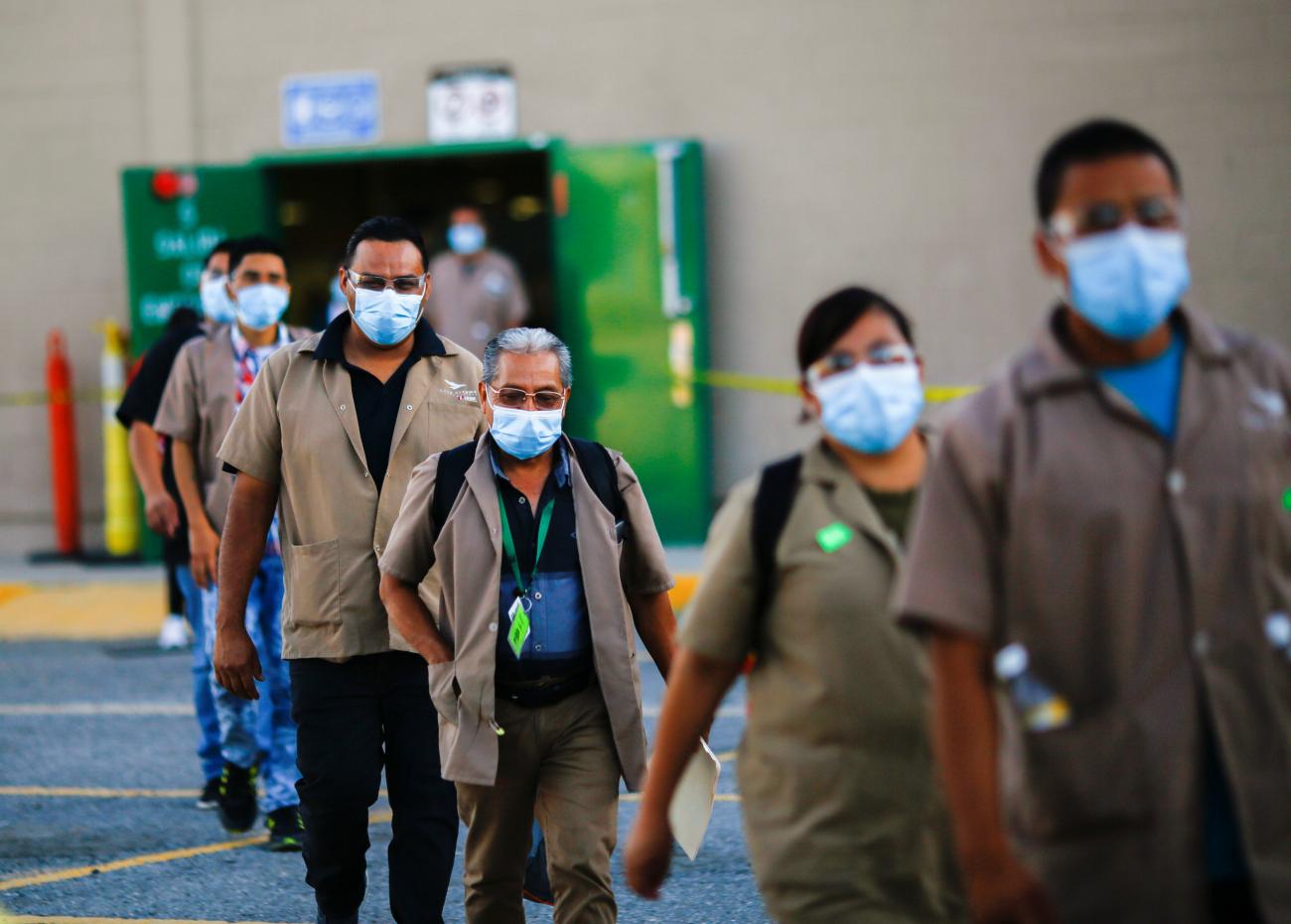 health-care workers walk in a line wearing masks.