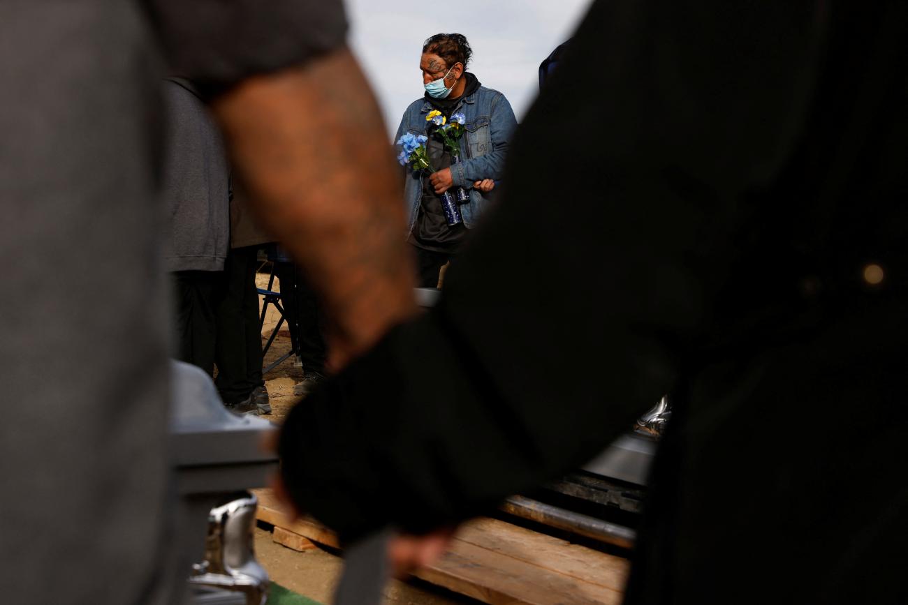 Two people hold hands during a funeral