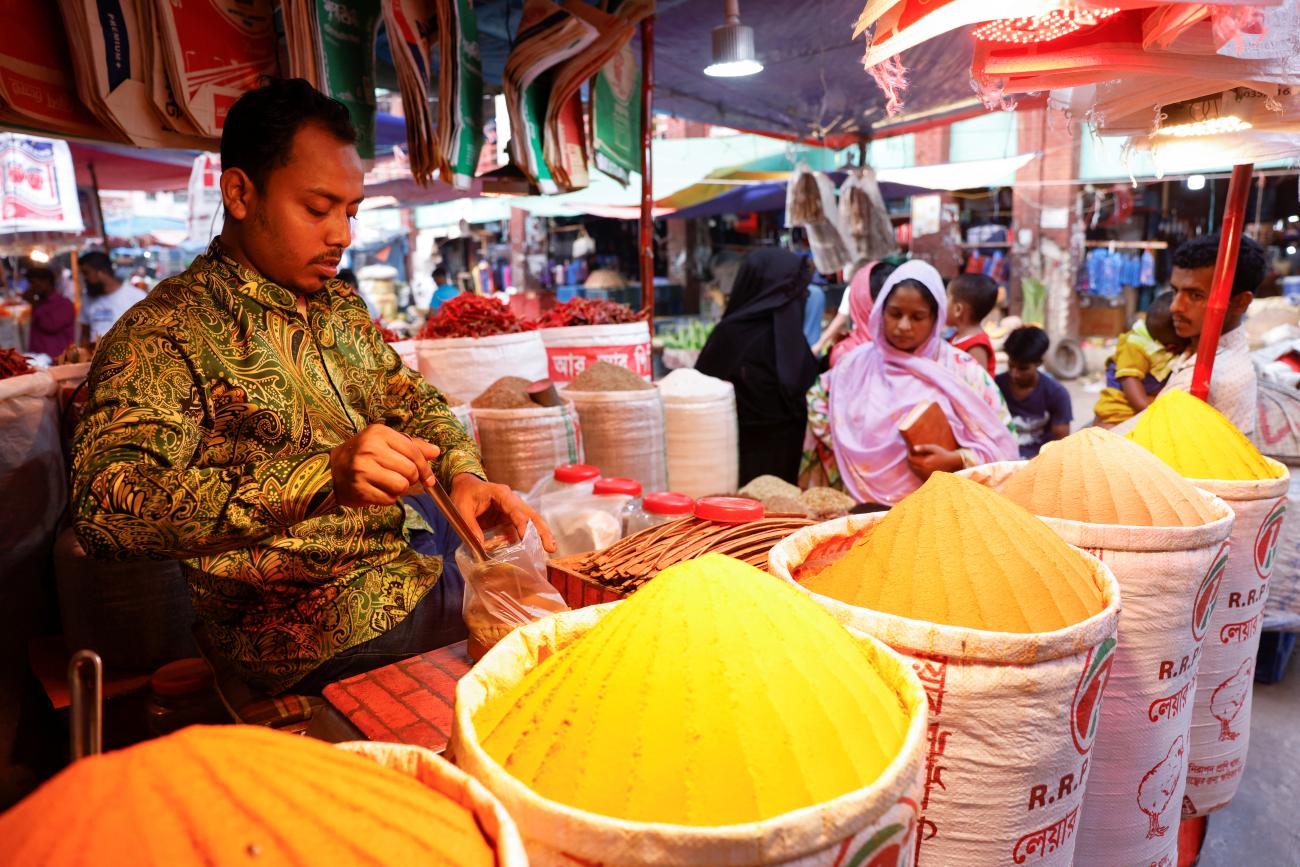 Man is seen in front of multiple piles of spices 