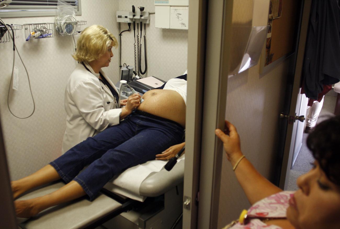 A woman receives an ultrasound in a patient room.